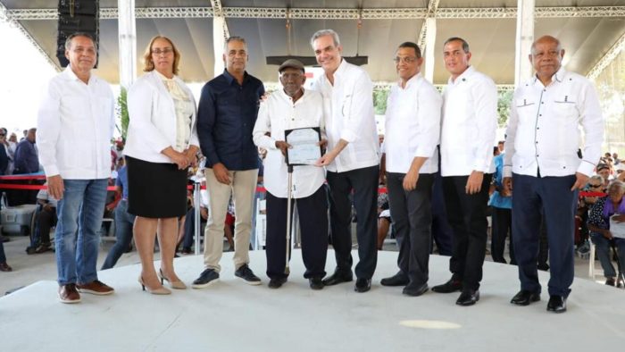 foto del presidente Luis Abinader, haciendo entrega de un titulo de propiedad a uno de los asistentes